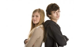 Teenage couple standing with arms crossed